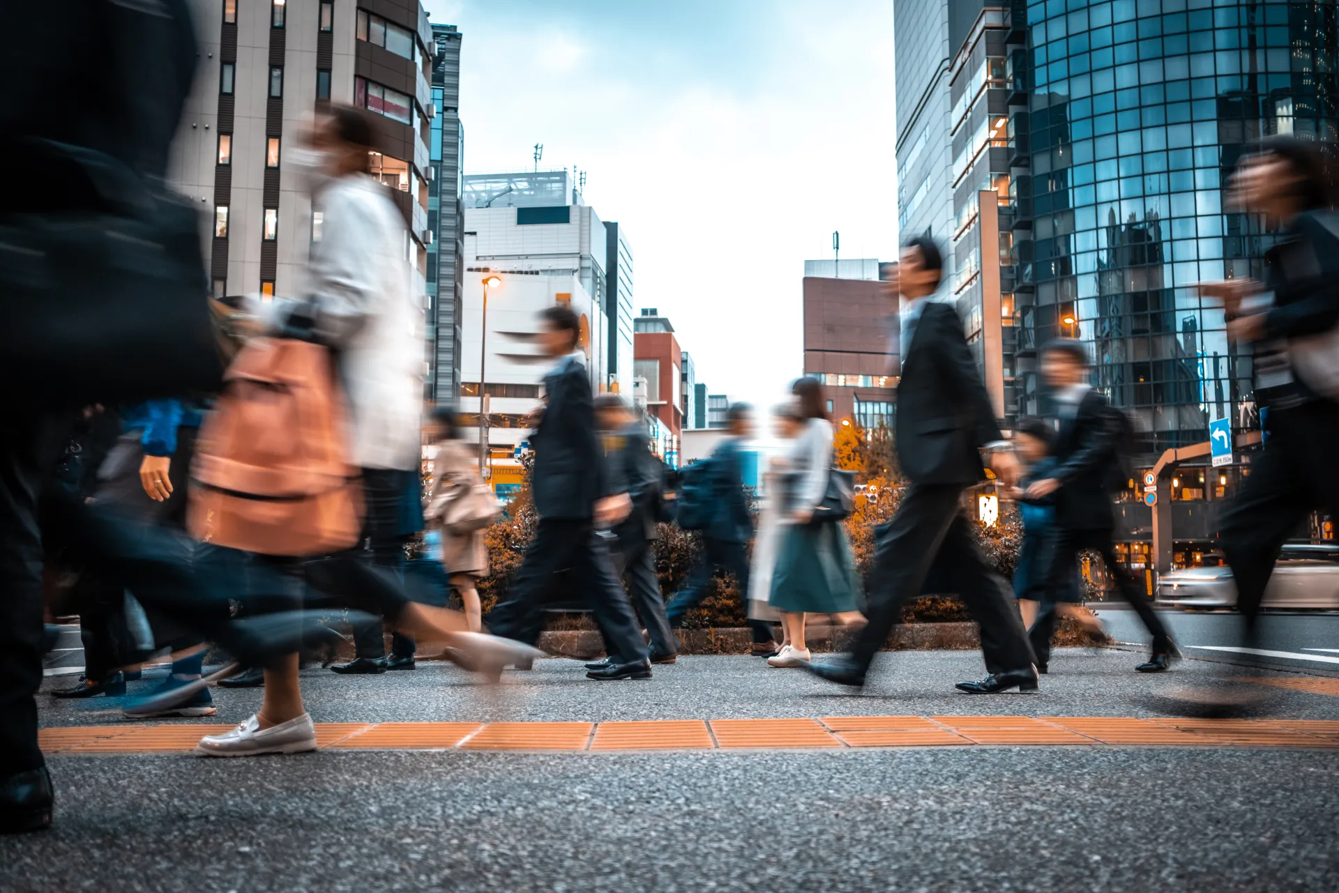A photograph of busy people crossing the street